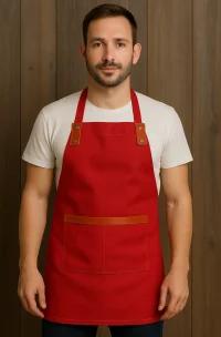 Delantal de cocina rojo en gabardina con aplicaciones de cuero café, diseño ajustable con bolsillo frontal, ideal para uso profesional en Chile